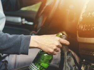 a driver is holding a bottle of alcohol while driving